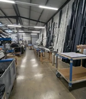 Intérieur d'entrepôt avec tables de production et rayonnages de matériaux.